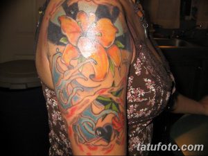 Фото тату: красочная татуировка с изображением цветов, бабочки и абстрактных элементов на руке девушки.