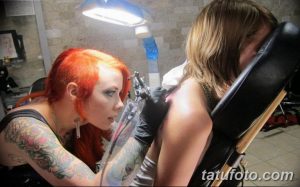 Фото: мастер тату делает татуировку девушке в тату-салоне.