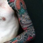 Фото тату маски Они на руке, выполненное в ярких цветах с использованием традиционных японских мотивов. Детализированный рисунок.