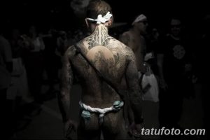 Фото тату на спине мужчины, выполненное в традиционном стиле с использованием черных линий и узоров. Вид сзади, демонстрирующий масштаб рисунка.