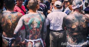 Фотография нескольких мужчин, покрытых сложными японскими татуировками, демонстрирующая традиционное искусство и масштабность рисунков.
