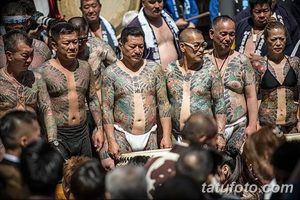 Фотография группы японских мужчин с традиционными татуировками Ирэзуми, покрывающими большую часть их тел. Видны сложные узоры и яркие цвета.