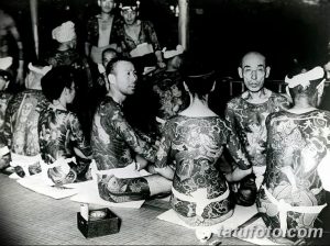 Фотография, демонстрирующая традиционные японские татуировки Ирэзуми на телах мужчин. Исторический снимок, показывающий масштаб и детализацию татуировок.