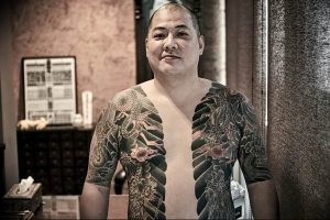 Фото тату японского дракона и волн, покрывающих большую часть тела мужчины. Детализированный рисунок в традиционном японском стиле.