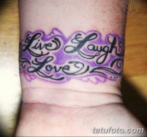 Фото тату надписи 'Live Laugh Love' выполненной фиолетовым цветом на запястье. Надпись украшена витиеватыми узорами.