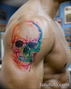 Фото акварельной татуировки черепа на плече. Мягкие переходы цветов, размытые контуры и эффект брызг краски.