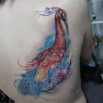 Фото акварельной татуировки феникса на спине. Красочный рисунок татуировки с использованием акварельной техники и ярких оттенков. Идеи для тату.