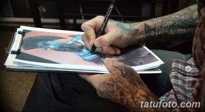 Фото тату: мастер тату рисует эскиз татуировки на бумаге, используя карандаш. Ручная работа над эскизом.