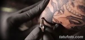 Фото процесса нанесения татуировки на голову. Мастер в черных перчатках работает над сложным рисунком, клиент сидит в кресле. Детализированный снимок.