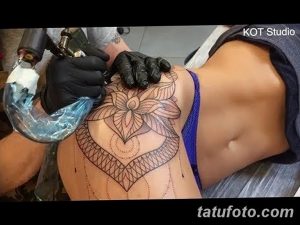 Фото процесса нанесения геометрической татуировки на плечо. Мастер в перчатках работает над сложным узором, используя тату-машинку. Детализированный снимок.