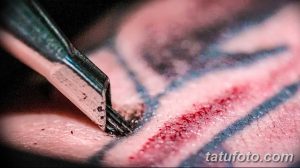 Фото тату процесса нанесения рисунка. Крупный план тату-машинки, работающей над кожей клиента, вид сверху.