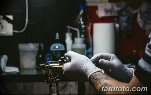 Фото рабочего места мастера тату. Видна тату-машинка, бутылочки с жидкостью, перчатки и другие инструменты.