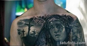 Фото тату Девы Марии с распятием на груди. Черно-белый рисунок в реалистичном стиле с религиозной символикой и драматичным выражением.