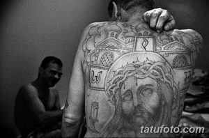 Фото тату Иисуса Христа в терновом венце на спине мужчины. Детализированный рисунок с религиозными символами и иконами.