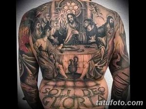 Фото тату Тайной вечери на спине. Детализированный рисунок с изображением Иисуса Христа и его апостолов за столом. Разнообразная цветовая палитра.