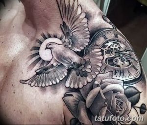 Черно-серая татуировка на плече с изображением летящего голубя, карманных часов и розы. Детализированный рисунок татуировки, выполненный опытным мастером.