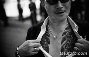 Фото черно-белой татуировки на груди: череп, обвитый розами. Детализированный рисунок с использованием теней и светотени.