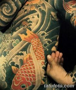 Фото тату: красочный карп кои, плывущий среди волн, татуировка выполнена на стопе.