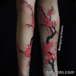 Фото тату ветки цветущей сакуры на ноге. Изображены нежные розовые цветы и тонкие ветви.