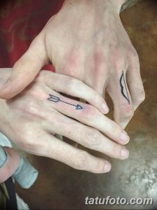Фото парных татуировок на руках: черная стрела на одной руке и контур лука на другой. Минималистичный дизайн, символизирующий любовь и единство.