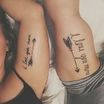 Фото парных тату на предплечьях: стрелы с перьями и надписью 'I love you more'. Минималистичный дизайн, черные чернила.