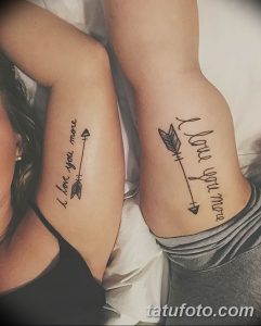 Фото парных тату на предплечьях: стрелы с перьями и надписью 'I love you more'. Минималистичный дизайн, черные чернила.