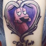 Фото тату с персонажем мультфильма 'Courage the Cowardly Dog' в форме сердца. Яркие цвета, мультяшный стиль, татуировка на плече.