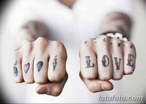 Фото тату на пальцах: сердце, бриллиант, молния и надпись LOVE. Минималистичный дизайн, черные чернила, современный стиль.