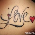 Фотография татуировки на спине, изображающей слово 'Love' с сердечками вместо букв 'o'. Черно-красный рисунок татуировки.