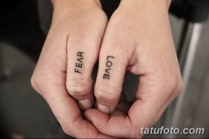 Фотография татуировок на пальцах рук, на одной руке надпись 'FEAR', на другой - 'LOVE'. Черно-белые татуировки с простым шрифтом.