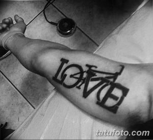 Фото тату: оригинальная надпись 'LOVE', буквы которой стилизованы под раму велосипеда, выполнена на предплечье в черно-белом цвете.