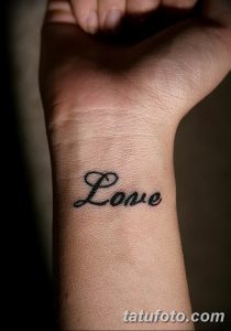 Фото тату надписи 'Love' черным цветом на внутренней стороне запястья. Минималистичный рисунок татуировки, выполненный четкими линиями.
