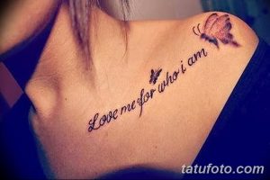 Фото тату надписи "Love me for who I am" с изображением двух бабочек, расположенной на ключице. Романтичный и вдохновляющий дизайн.