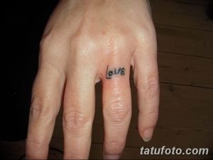 Фото маленькой татуировки надписи 'Love' на пальце. Простой, минималистичный рисунок татуировки черным цветом. Идеально для тех, кто предпочитает небольшие тату.