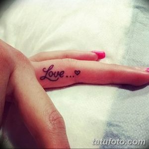 Фото тату надпись 'Love' с маленьким сердечком на пальце. Нежный и минималистичный рисунок татуировки для девушек.