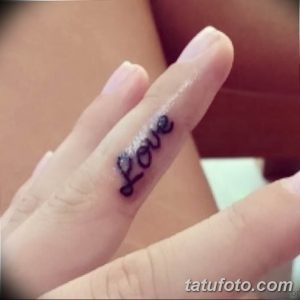 Фото тату надписи 'Love' на пальце, выполненной изящным шрифтом. Маленький рисунок татуировки, символизирующий любовь и привязанность.