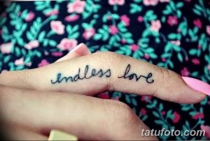 Фотография небольшой татуировки со словами 'endless love', выполненной на фаланге пальца. Черно-серая татуировка.