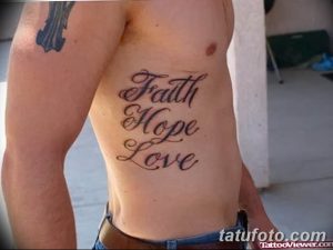 Фото татуировки с надписью 'Faith Hope Love' выполненной каллиграфическим шрифтом на боку мужчины. Черно-серый рисунок тату.