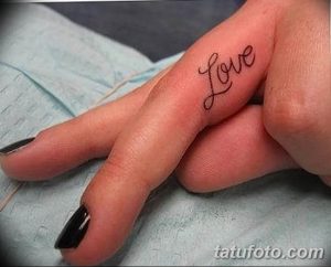 Фото тату на пальце: надпись 'Love' черными чернилами, выполненная в минималистичном стиле.