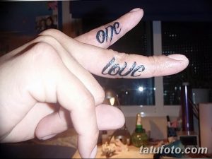 Фото тату на пальце: надпись 'one love' черными чернилами, выполненная в минималистичном стиле.