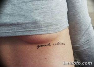 Фото тату: небольшая надпись "good vibes" на боку. Минималистичный рисунок татуировки.