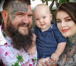 Фотография мужчины и женщины с татуировками на теле, держащих на руках младенца.