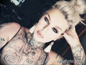 Фотография девушки с длинными светлыми волосами, украшенной татуировками на шее, груди и руках в стиле реализм.
