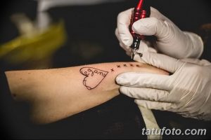 Фото минималистичной татуировки на руке, изображающей сердце с надписью "vegan" и небольшими крестиками.
