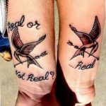 Фото парных татуировок птиц с раненными крыльями и надписью 'Real or Not Real?'. Черно-белые тату на предплечьях, символизирующие сомнения и выбор.