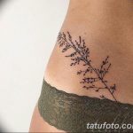 Фото тату: тонкая черная татуировка с изображением веточки с листьями на женском бедре. Минималистичный и элегантный рисунок татуировки.