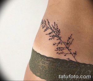 Фото тату: тонкая черная татуировка с изображением веточки с листьями на женском бедре. Минималистичный и элегантный рисунок татуировки.
