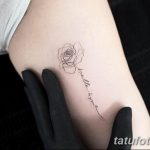 Фото изящной татуировки с изображением розы и надписи 'bella ama' на руке. Рисунок выполнен тонкими линиями в черно-сером цвете.