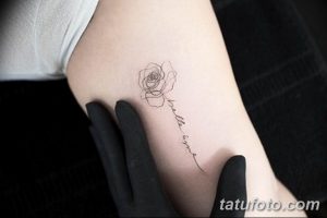Фото изящной татуировки с изображением розы и надписи 'bella ama' на руке. Рисунок выполнен тонкими линиями в черно-сером цвете.