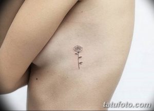 Фото тату маленькой черной розы на боку. Простой и элегантный рисунок татуировки, выполненный в технике лайнарт.